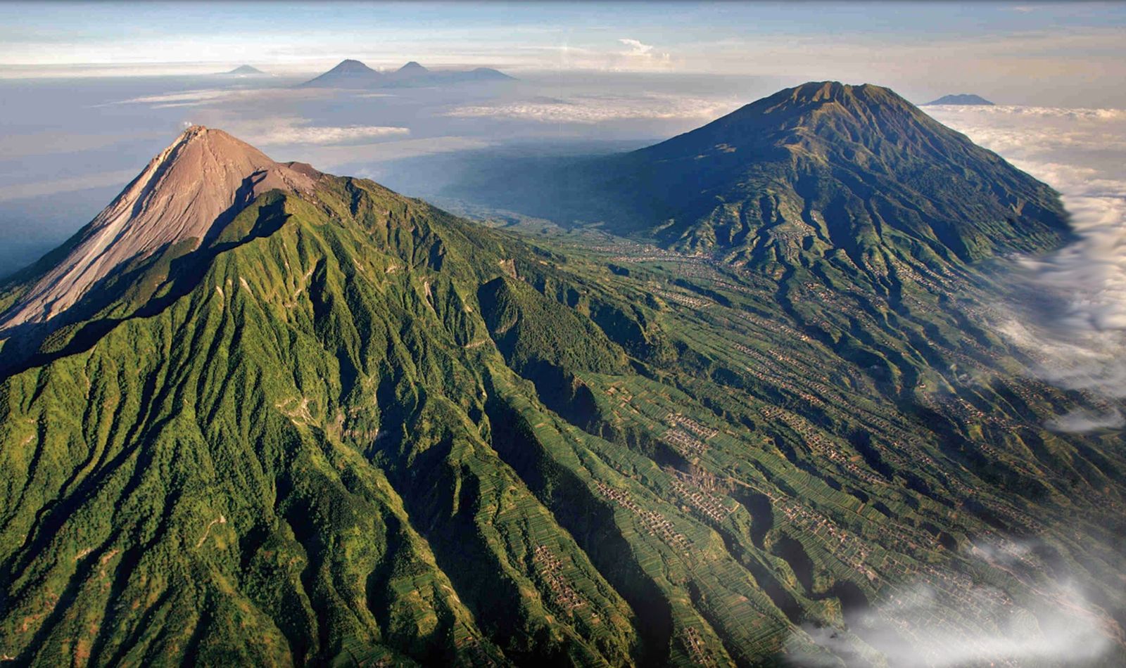 上空から見たMerapi山（手前）とJava島中部の円錐形の火山