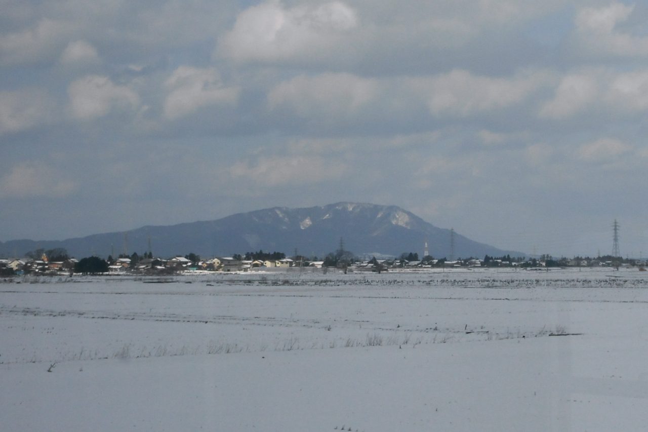 雪をかぶった平野の向こうに山が見える（新潟県・越後平野）