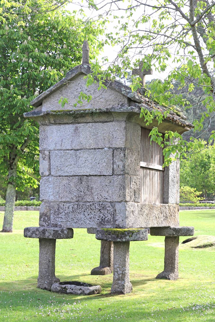 Un hórreo elevado sobre postes de piedra, con piedras planas antirroedores en la parte superior (Galicia)